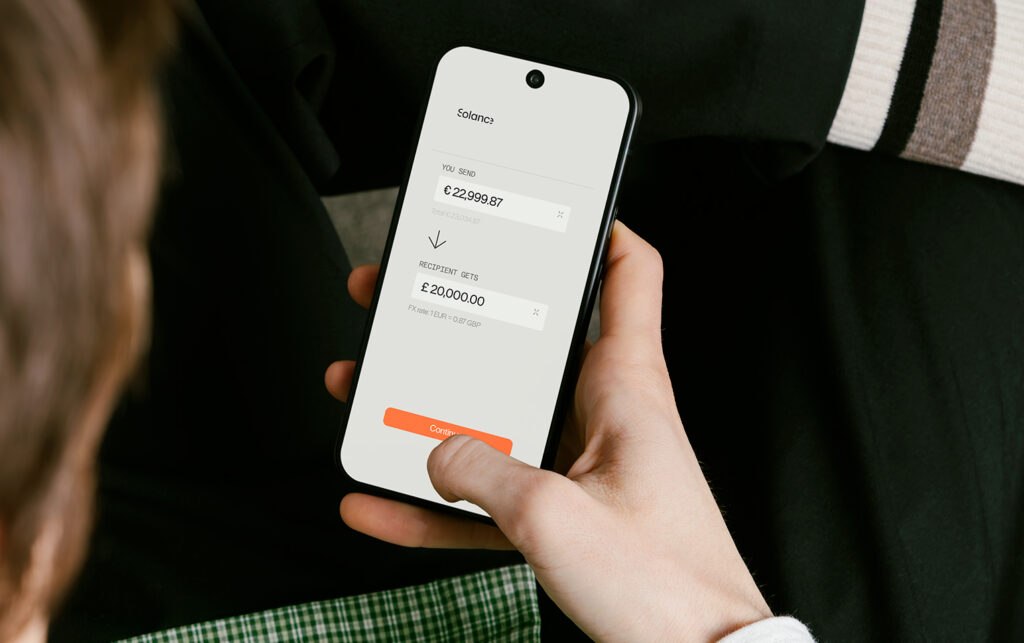 Person holding a phone displaying Solance foreign exchange and multi-currency management